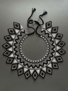 a black and white beaded necklace with tassels hanging from it's center