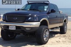 a black truck parked on top of a sandy beach