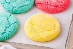 four colorful cookies sitting on top of a baking sheet