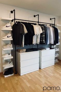 an organized closet with white drawers and black clothes hanging on the rail, along with shoes