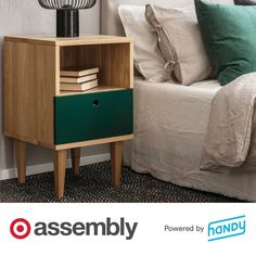 a nightstand with books on it next to a bed and pillows in a room that says assembly powered by handy