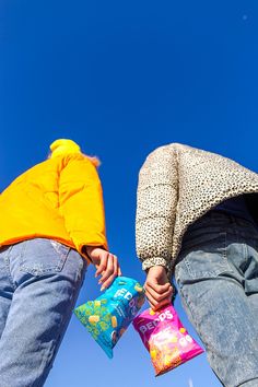 two people are holding their hands together while standing on the grass and looking up in the sky