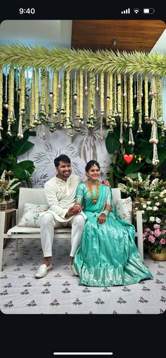 a man and woman sitting on a bench in front of a floral display with flowers