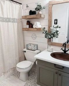 a white toilet sitting next to a sink in a bathroom under a mirror and wooden shelves