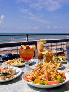 plates of food and drinks on a table overlooking the ocean