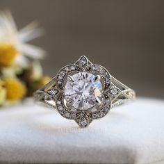 a white diamond ring sitting on top of a table next to yellow and white flowers