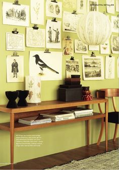 a wooden table sitting in front of a wall covered with pictures and artwork on it