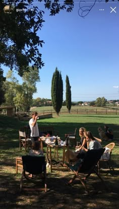 several people sitting around a table in the shade on a sunny day at a farm