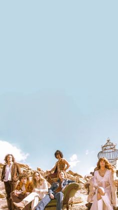 a group of people sitting on top of a pile of dirt next to a birdcage