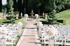 an outdoor ceremony setup with white chairs and flowers