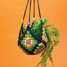 a crocheted bag hanging from a tree branch with green leaves and yellow background