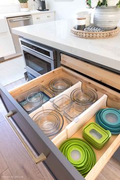 an open drawer in the middle of a kitchen with plates and bowls on top of it