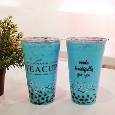 two blue cups sitting on top of a table next to a potted green plant