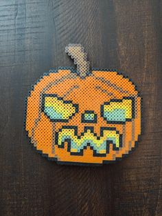 a perler bead pumpkin with an evil face