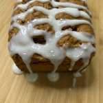 a loaf of bread covered in icing sitting on top of a wooden table