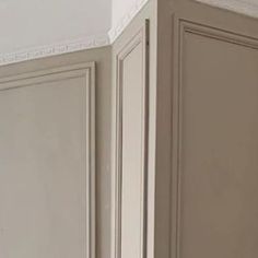 the corner of a kitchen cabinet with white trim and molding on the wall above it