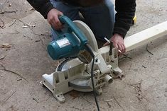 a man using a circular saw to cut wood with an electric grinder on the ground