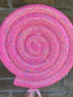 a pink paper plate with sprinkles on it sitting in front of a brick wall