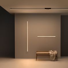 an empty room with a bench and some lights on the wall, in front of a gray wall