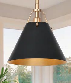 a black and gold pendant light hanging from a ceiling in a room with large windows