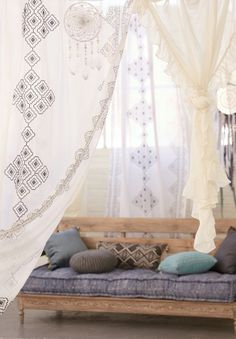 a wooden bench sitting in front of a window with curtains on the windowsills