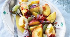 a white plate topped with sliced fruit and veggies next to a silver spoon