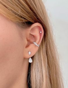 a close up of a woman's ear with two diamond earrings on top of it