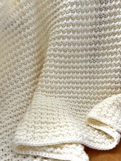 a white crocheted blanket laying on top of a wooden floor