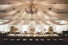 a banquet hall with white draping and chandelier