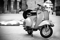 a scooter is parked on the sidewalk in black and white