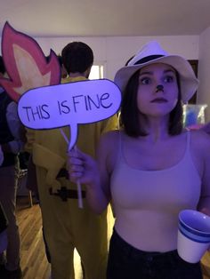 a woman holding a sign that says this is fine in front of other people at a party