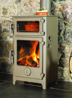 a stove that is sitting in front of a brick wall with a pot on top