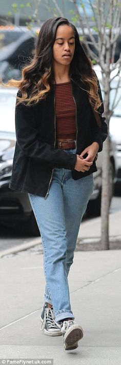 a woman walking down the street with her hand in her pocket