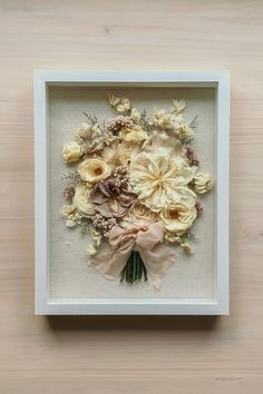 an arrangement of flowers is framed in a white frame