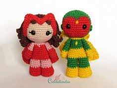 two crocheted dolls sitting next to each other on a white surface, one is red and the other is green