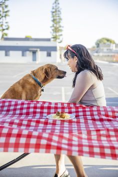 a woman sitting at a picnic table with her dog