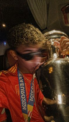 a young man drinking from a large metal cup