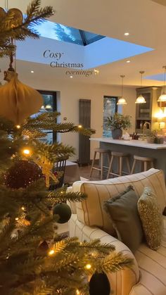 a living room filled with furniture next to a christmas tree in front of a kitchen