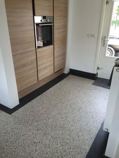 an empty room with a stove and cabinets in the corner, next to a door