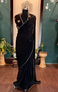 Beautiful black chinnon sari with  all over sequins and scalloped edges with an elegant dola silk brocade blouse saree fabric:chinnon length:5.5 meters blouse: 1m dola silk brocade black petticoat included Size: please choose a standard size from the drop down or you can choose custom measurements.  I'll send you a detailed measurements chart once you order. Traditional Georgette Pre-draped Saree For Celebration, Pre-draped Georgette Saree For Celebration, Festive Black Pre-draped Saree With Cutdana, Elegant Black Chanderi Saree, Fitted Dola Silk Saree With Dori Work, Fitted Dola Silk Pre-draped Saree With Dori Work, Elegant Black Art Silk Saree, Black Art Silk Traditional Wear For Party, Black Art Silk Traditional Party Wear