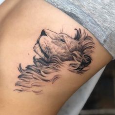 a woman's thigh with a tattoo of a lion on the side and her hair blowing in the wind