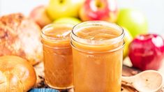 two jars filled with apple cider sitting on top of a table next to bread