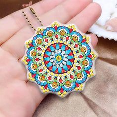 a hand holding a colorful medallion shaped keychain