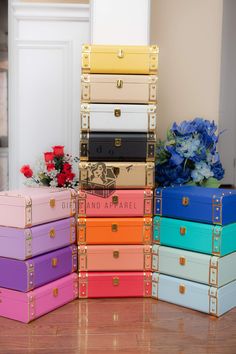 five different colored trunks stacked on top of each other in front of flowers and vases