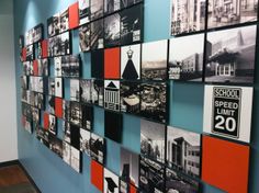 a wall with many pictures on it in an office building's hallway, showing the number 20