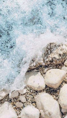 rocks and sand on the beach with water splashing over them