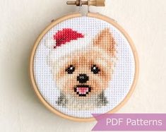 a small dog with a santa hat on it's head cross stitched into a hoop