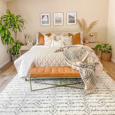 a bedroom with a bed, plant and pictures on the wall