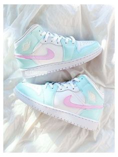 a pair of white and pink sneakers on top of a bed