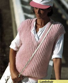 a man wearing a pink sweater vest and hat